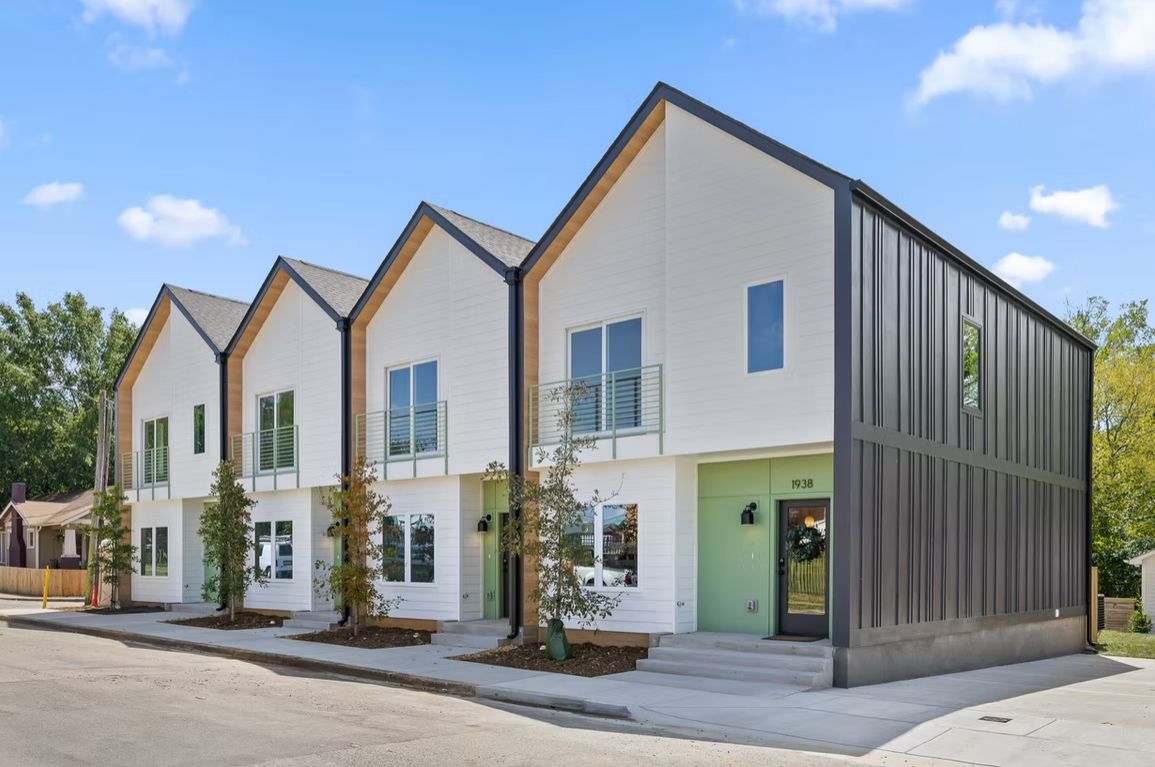 Four finished attached homes on Beech Street with white siding, gabled roofs and a dark standing-seam end wall, seen from the corner