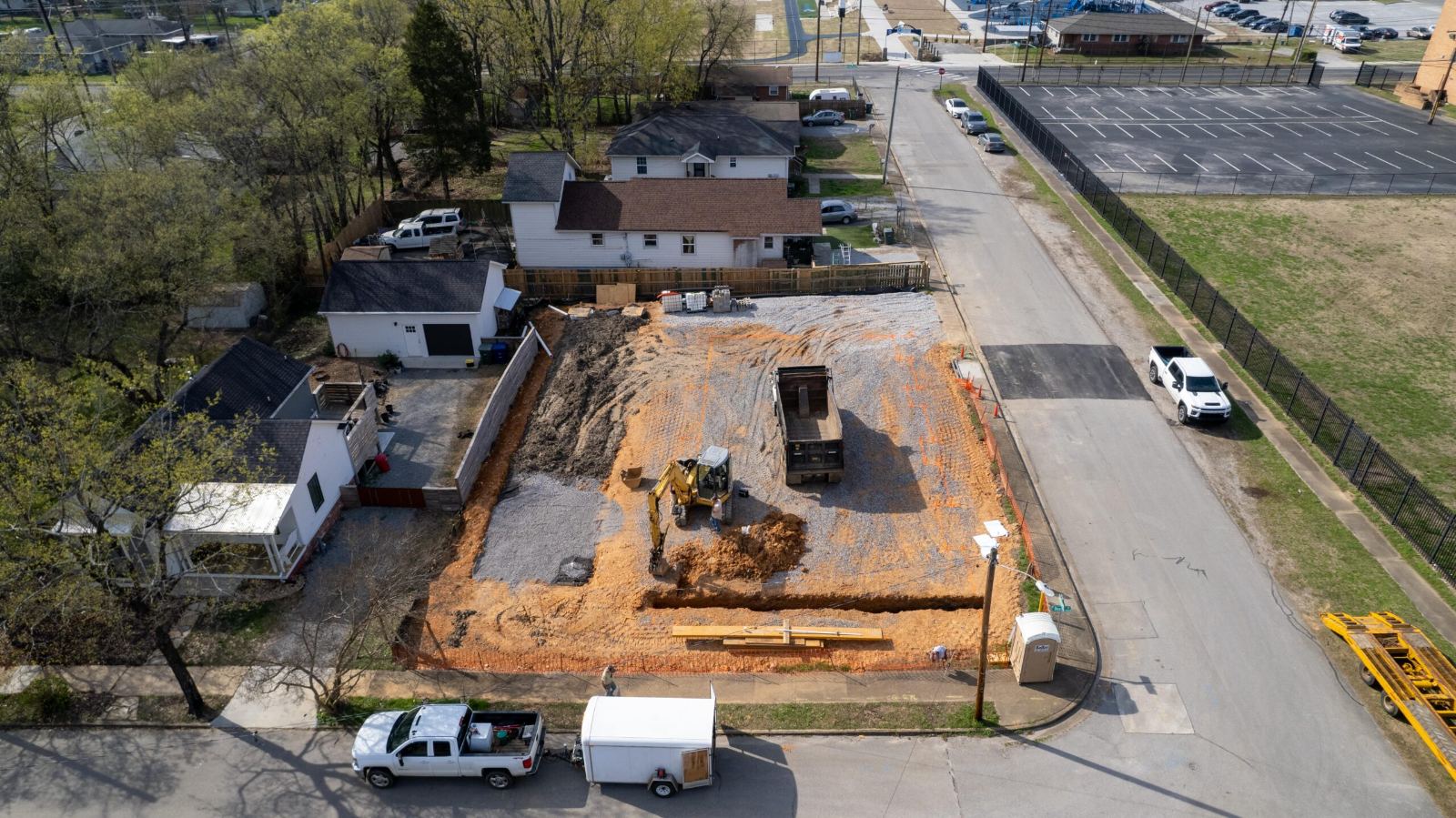 Aerial view of the excavated Beech Street lot from the street side, with the stone pad graded and trenches cut along the property line
