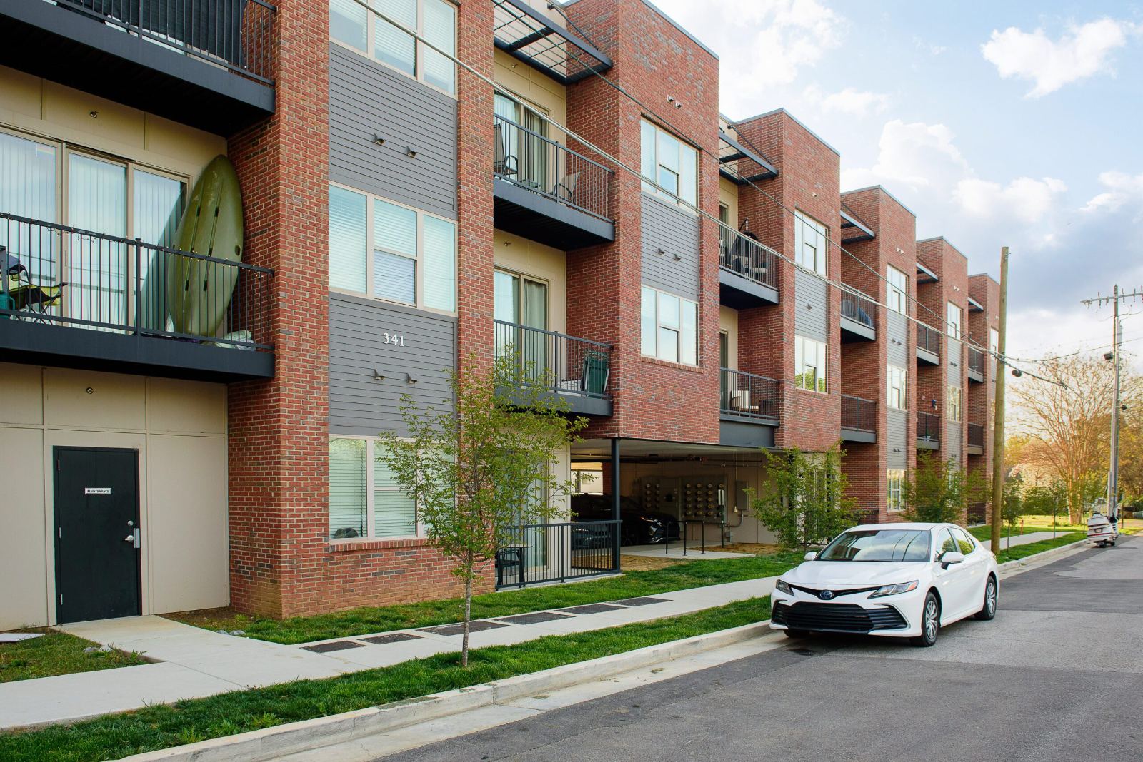 The brick and panel facade at 548 Cherokee Boulevard from the side street, with stepped bays, balconies, a lawn strip and the covered parking level below